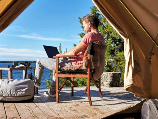 Photo of a man in a glam tent working on a lap top